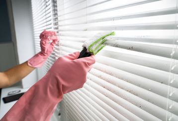 Careful cleaning of wooden blinds using a microfiber cloth to preserve the natural beauty.